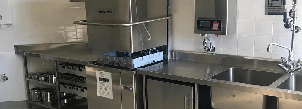 Commercial kitchen with a stainless pass-through dishwasher and sinks