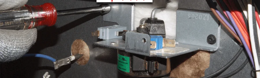 Technician using a screwdriver on an oven door-lock mechanism